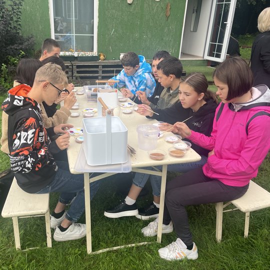 Vaikai prie lauko stalo dekoruoja meduolius