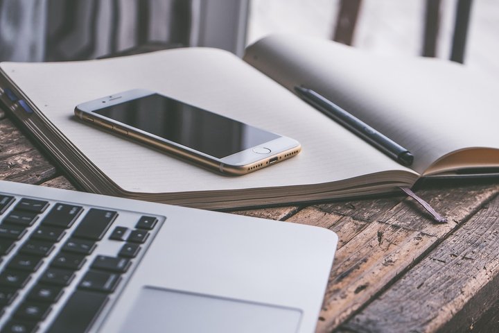 Darbo vieta su atverstais popieriais ir mobiliuoju telefonu ant stalo