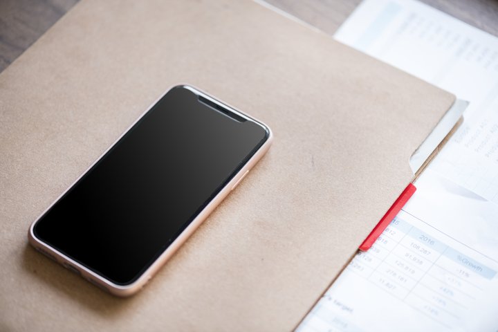 Mobilusis telefonas guli ant popierių segtuvo